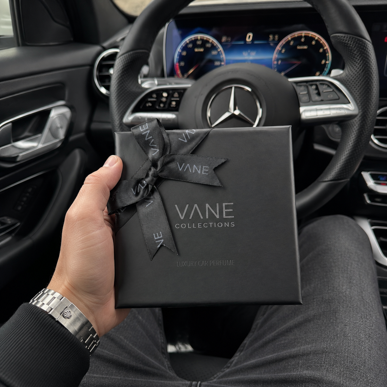 Minimalistische luxe auto parfum van VANE Collection met zwart geurzakje en premium verpakking op een donkere auto-interieur achtergrond in quiet luxury stijl.